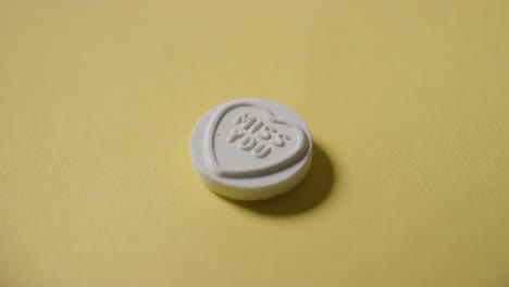 노란색 배경에 당신이 그리워요 메시지와 함께 심장 사탕을 손에 들고