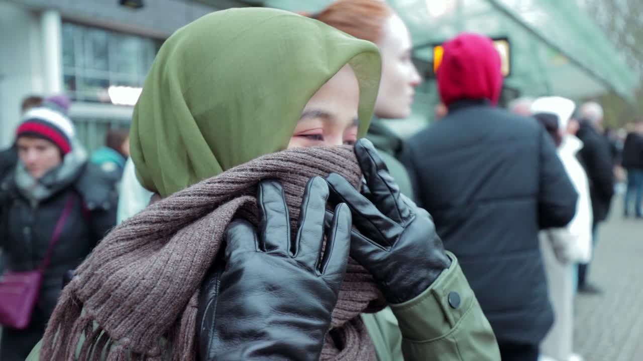 Muslim Woman in Green Jacket Cover Her Nose from Cold