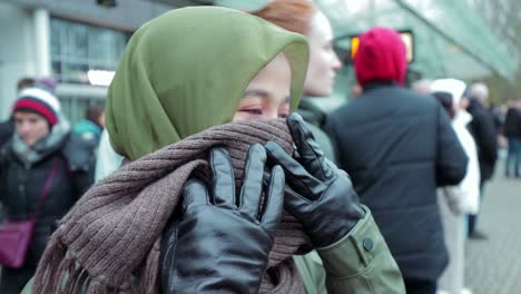 muslim woman in green jacket cover her nose from cold
