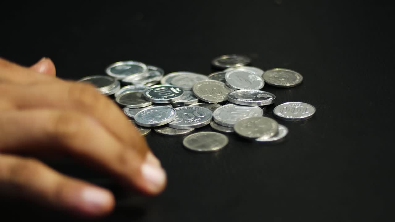 close up of tidying up a pile of coins on the table