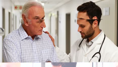 Doctor-comforting-senior-patient-in-corridor