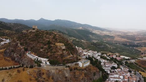 Toma-Aérea-Del-Castillo-Medieval-En-La-Cima-De-Una-Colina-Y-La-Ciudad-Tradicional-De-Casas-Blancas