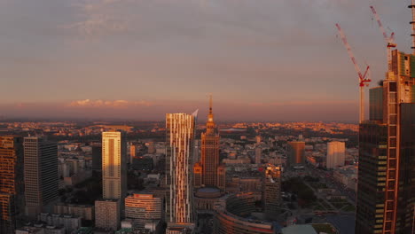 Slide-and-pan-footage-of-downtown-high-rise-buildings-in-last-sun-rays-of-day.-Historic-PKIN-building-at-sunset.-Warsaw,-Poland