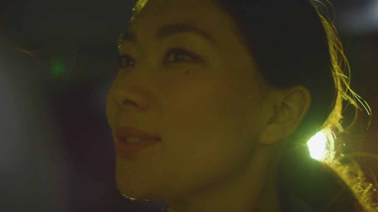 primer plano de una mujer que visita e interactúa con una exposición de arte inmersiva iluminada por la luz del proyector 9