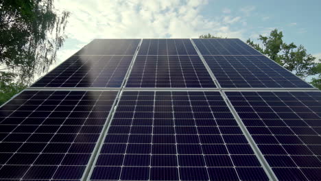 Tilt-up-close-up-along-photovoltaic-solar-panels-facing-cloudy-blue-sky