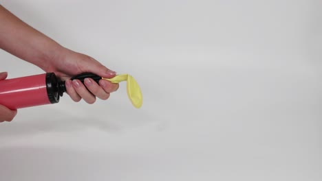 inflating yellow balloon with pump, then releasing it