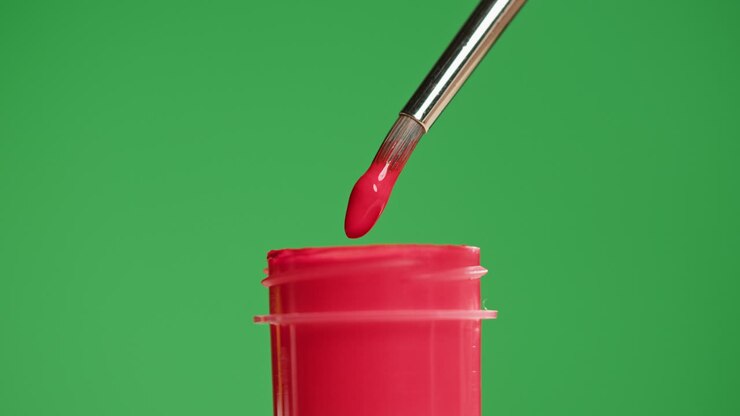 Pennello che si immerge nella vernice rossa e gocciola su schermo verde.