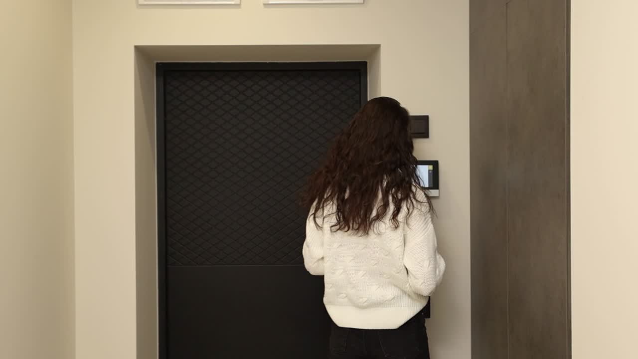 Woman using a digital device at the door in an apartment