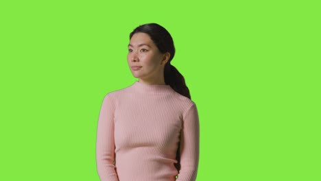 studio portrait of woman looking all around frame against green screen