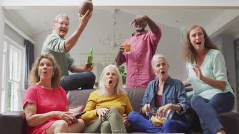 animation of happy diverse senior friends cheering while watching american football match in tv