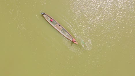 a longboat sailing on the green waters of florencia,, man fishing colombia, aerial view