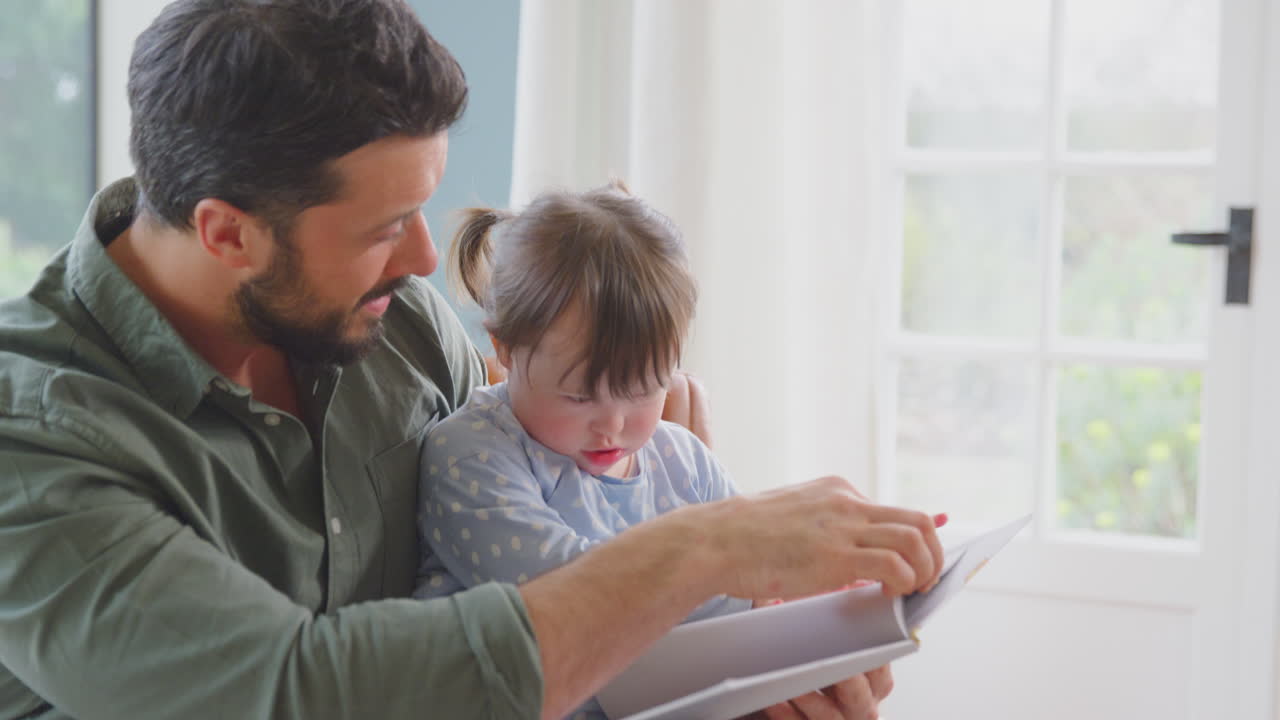 padre con síndrome de down hija leyendo un libro en casa juntos