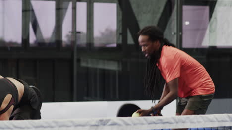 man playing padel tennis on indoor court, focusing on hitting ball with paddle