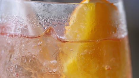detailed view of a citrus slice submerged in a chilled, bubbly beverage with visible condensation.