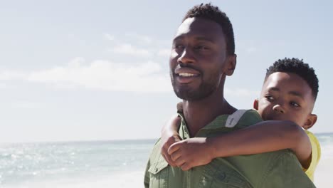 Lächelnder-Afroamerikanischer-Vater-Und-Sohn-Umarmen-Sich-Am-Sonnigen-Strand