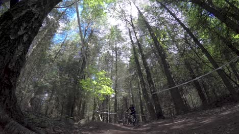 Ciclista-De-Montaña-Montando-Cuesta-Abajo-A-Alta-Velocidad-En-Pista-Forestal,-Curvando-Alrededor-De-Las-Bermas-De-Las-Esquinas