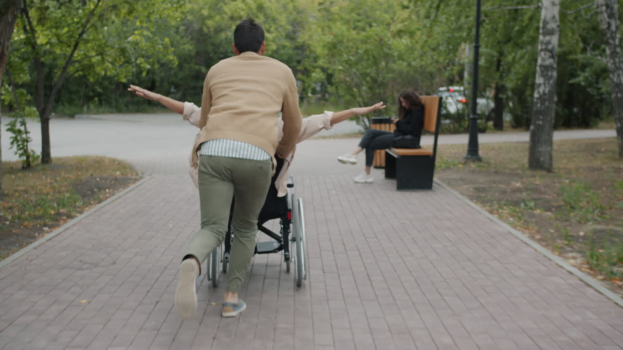 Man pushing woman in wheelchair