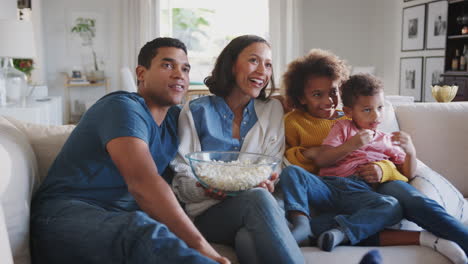 Joven-Familia-Afroamericana-Sentada-En-El-Sofá-De-Casa-Viendo-Televisión-Y-Comiendo-Palomitas-De-Maíz