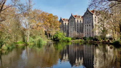 old building with reflection on lake water - parque d carlos i in portugal - slow motion revealing shot