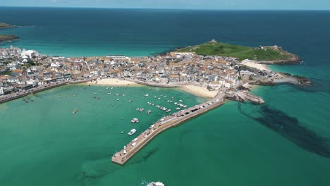 high aerial orbit of st ives with boat exiting the bay into calm turquoise sea