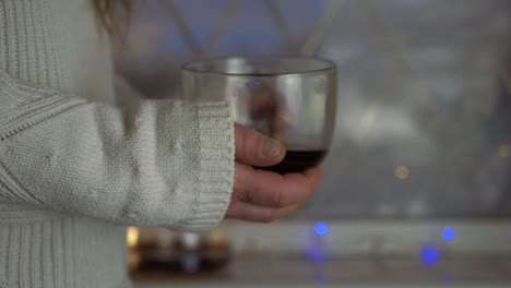 woman with mug of fresh brewed coffee with christmas lights background medium shot