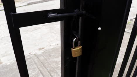 hands removing a key padlock and opening gate