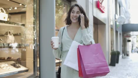 Latin-woman-talking-on-mobile-phone-and-watching-shop-windows