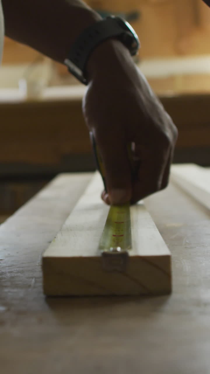 video de las manos de un carpintero afroamericano mayor midiendo madera en un taller de carpintería