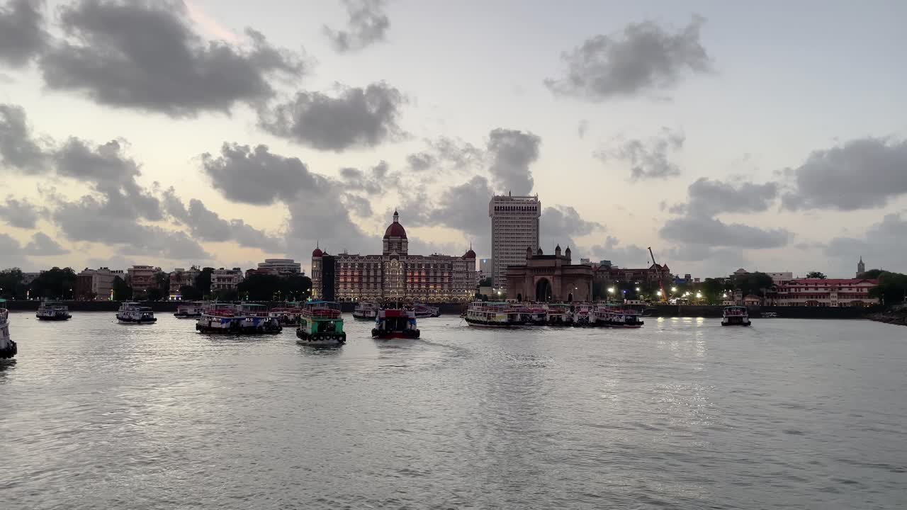 Boats docked near the iconic Gateway of India, with clouds overhead.