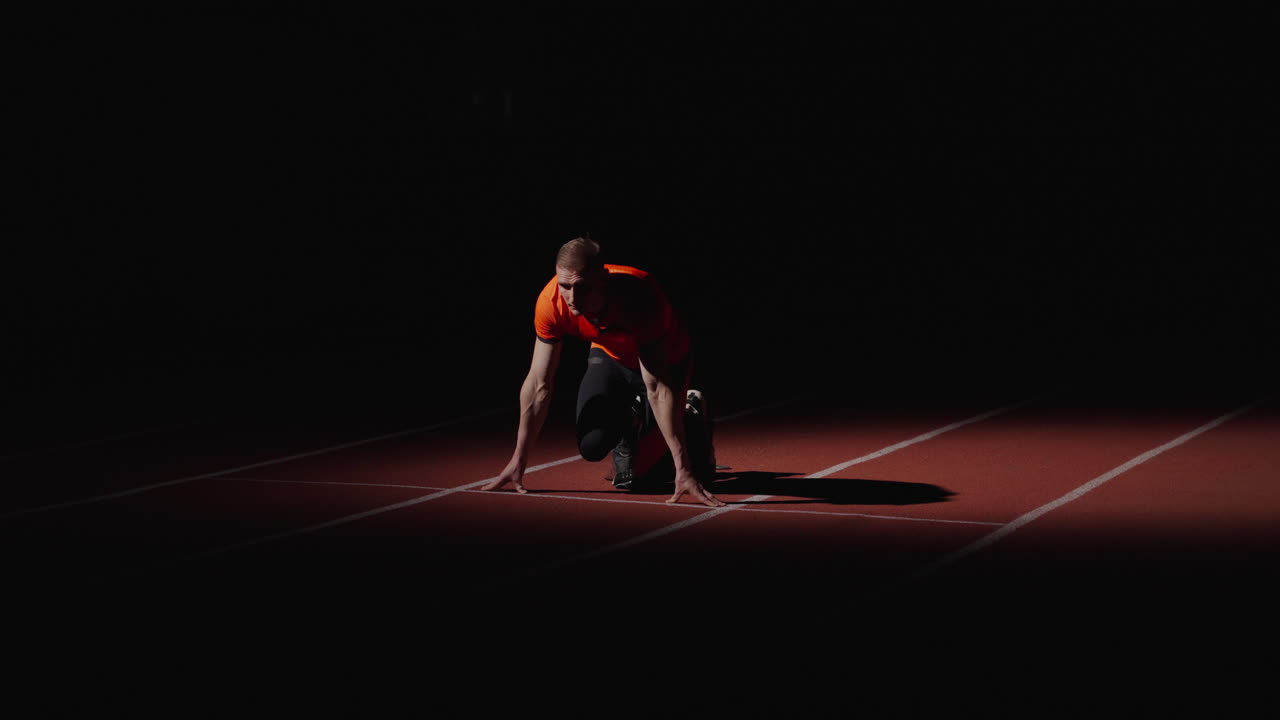 corredor en posición de salida en una pista por la noche