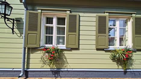 green wooden house wall with flower boxes and open white window shutters