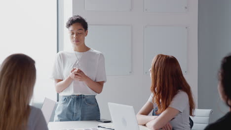 女性ボスがテーブルの周りに集まった女性ビジネスマンのチームにプレゼンテーションをするとき ⁇ ドアを通して見る