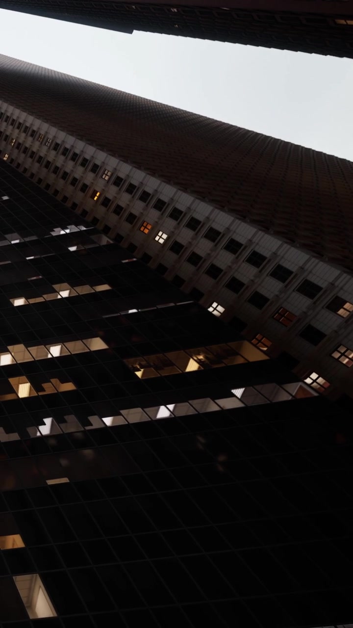 Tall buildings reach up against the sky in a city seen from below