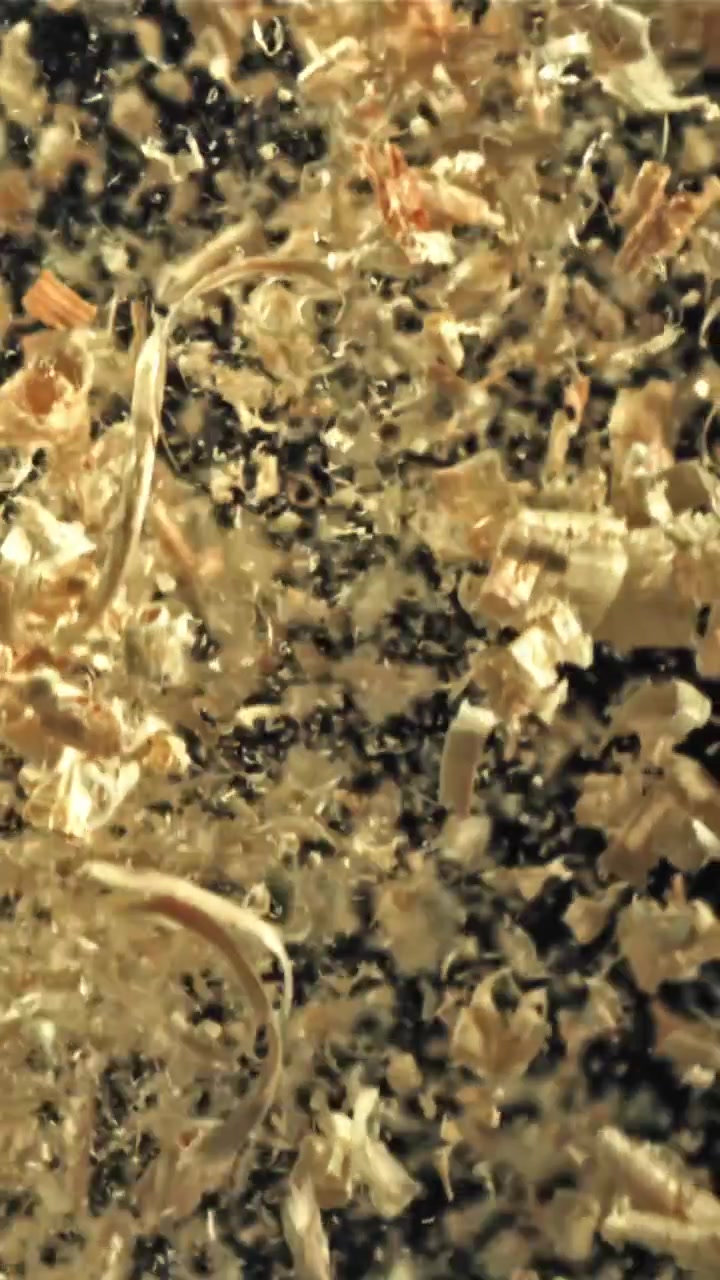 Nærbillede af træspåner og savsmuld der falder i slowmotion