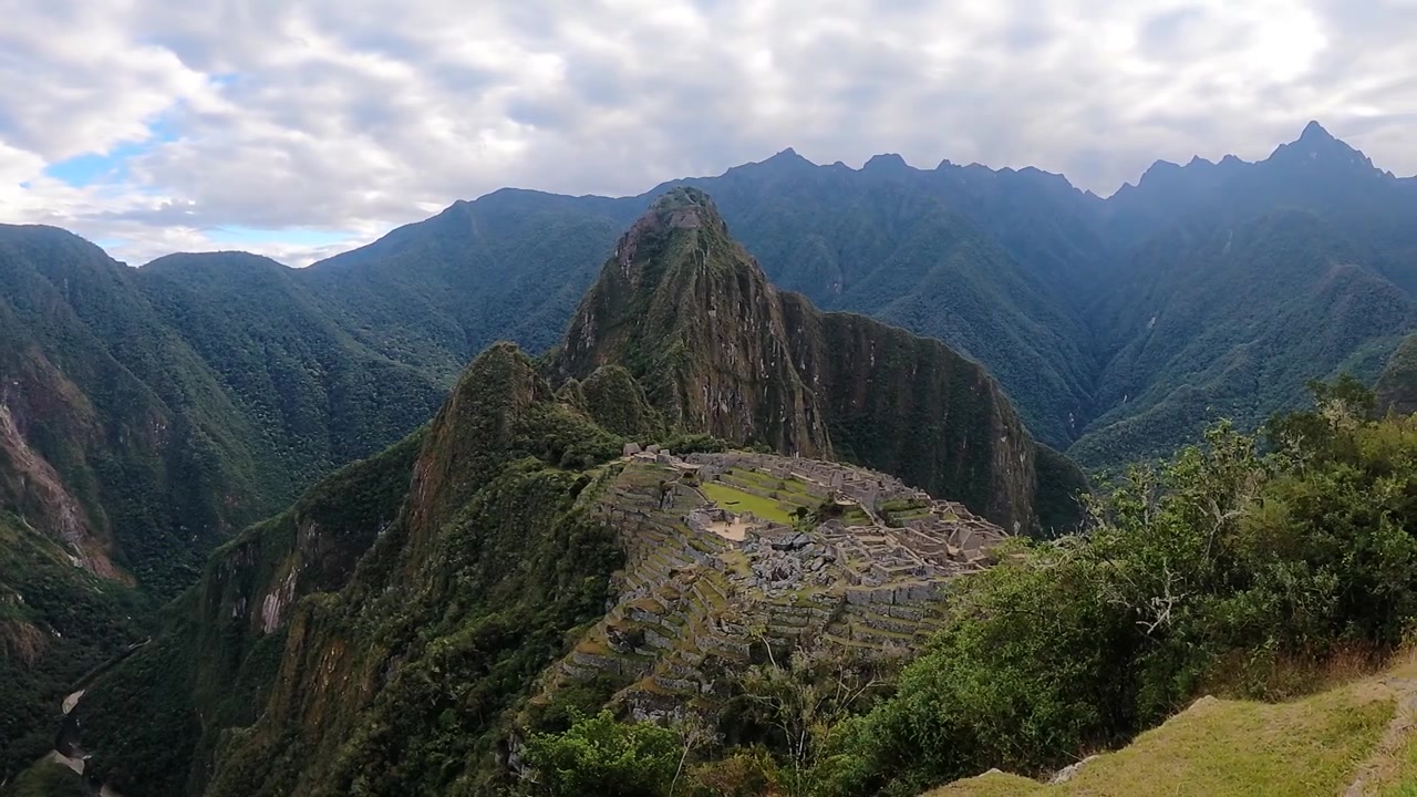 Turisti che fanno escursioni con vista sull'antica cittadella Inca e sulle montagne circostanti delle Ande