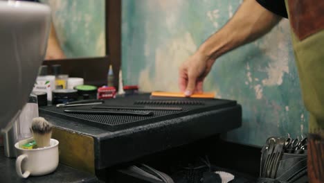 Close-Up-view-of-barber's-hands-placing-different-hair-brushes-and-combs-while-preparing-for-a-haircut