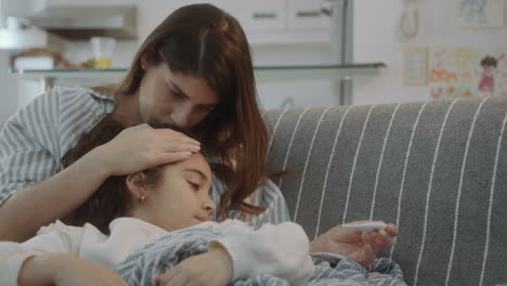 mother measuring body temperature of feverish child