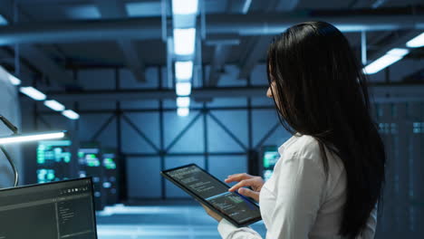 Woman-in-server-room-coding-on-tablet