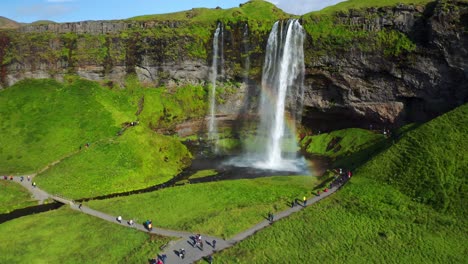 poderosa cascada de seljalandsfoss salpicando y creando arco iris en un día soleado en islandia - aéreo