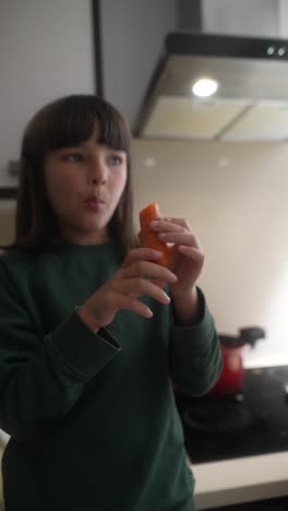 young girl holding a carrot in a kitchen
