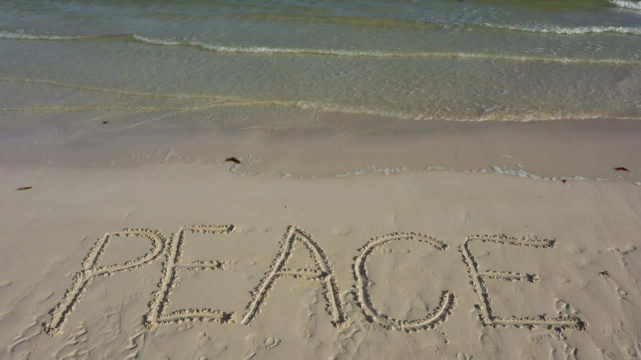 먼 거리에서 윈드서퍼와 함께 해변의 모래에 멕시코가 새겨져 있습니다.