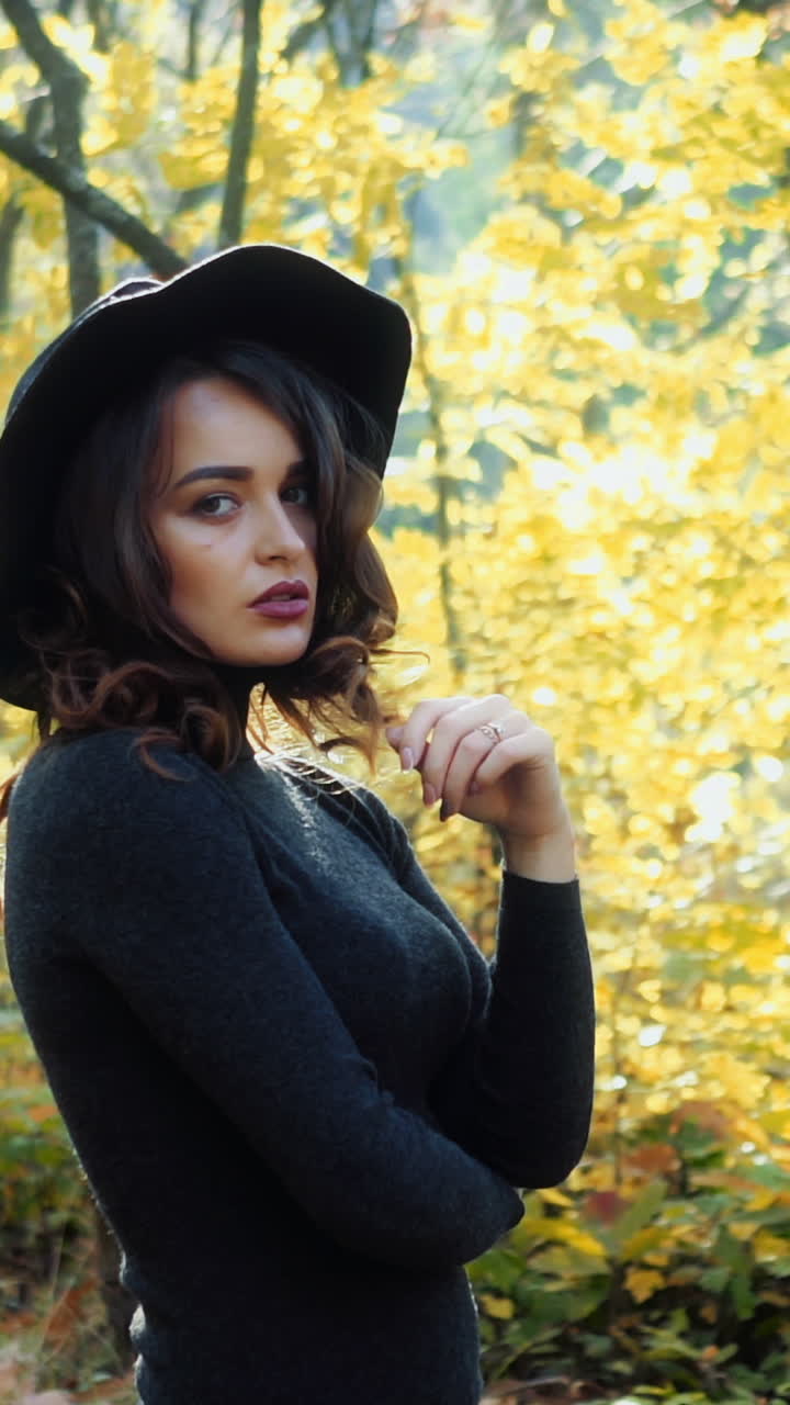 Sunny autumn day in park. Young woman spending time in autumn park Vertical video