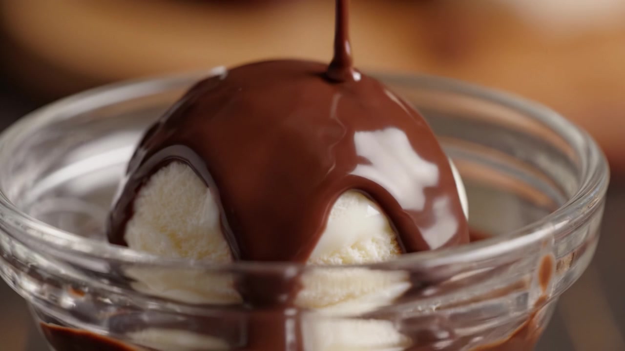 Una pallina golosa di cremoso gelato alla vaniglia con una ricca salsa al cioccolato che cola sopra, perfetta per gli amanti dei dolci in cerca di una delizia decadente.
