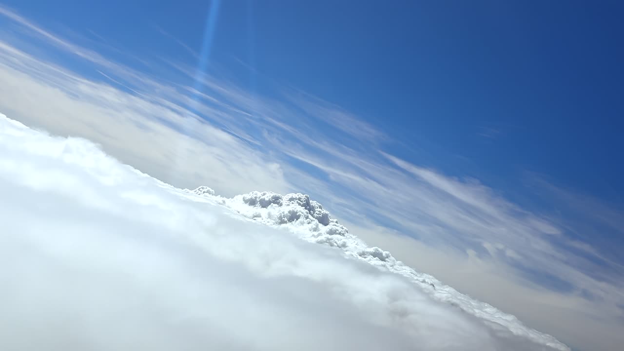 POV crossing a layer of clouds during the climb in a left turn, emerging to a glorious blue sky with sun rays reflecting in the pilot windshield. Ultra-realistic 4K