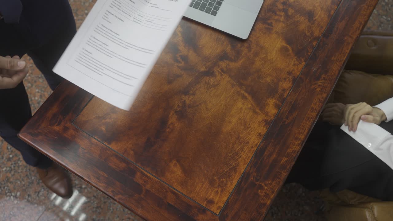 사무실에서 고용 계약서에 서명하는 알아볼 수 없는 직원과 상사의 상위 뷰