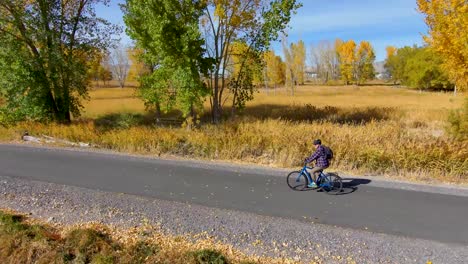 hombre mayor en bicicleta a lo largo de un sendero natural pavimentado en otoño - vista aérea