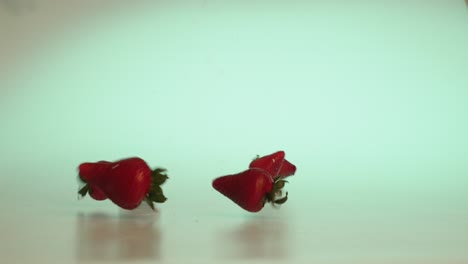 Dramatic-fall-of-fresh-and-juicy-strawberries-rolling-forward-and-bouncing-off-the-scene,-marketing-advertising-material-studio-concept-shot