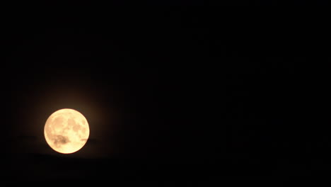 el paisaje lunar cicatrizado por cráteres se puede ver claramente como una rara súper luna azul se eleva a través de nubes oscuras en el lapso de tiempo