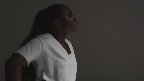 foto de perfil de estudio de una mujer joven bailando con iluminación baja contra un fondo gris 1