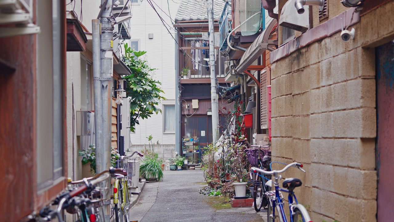 A vertical camera movement reveals the complex overhead power lines and old wooden houses of a quiet Tokyo backstreet.